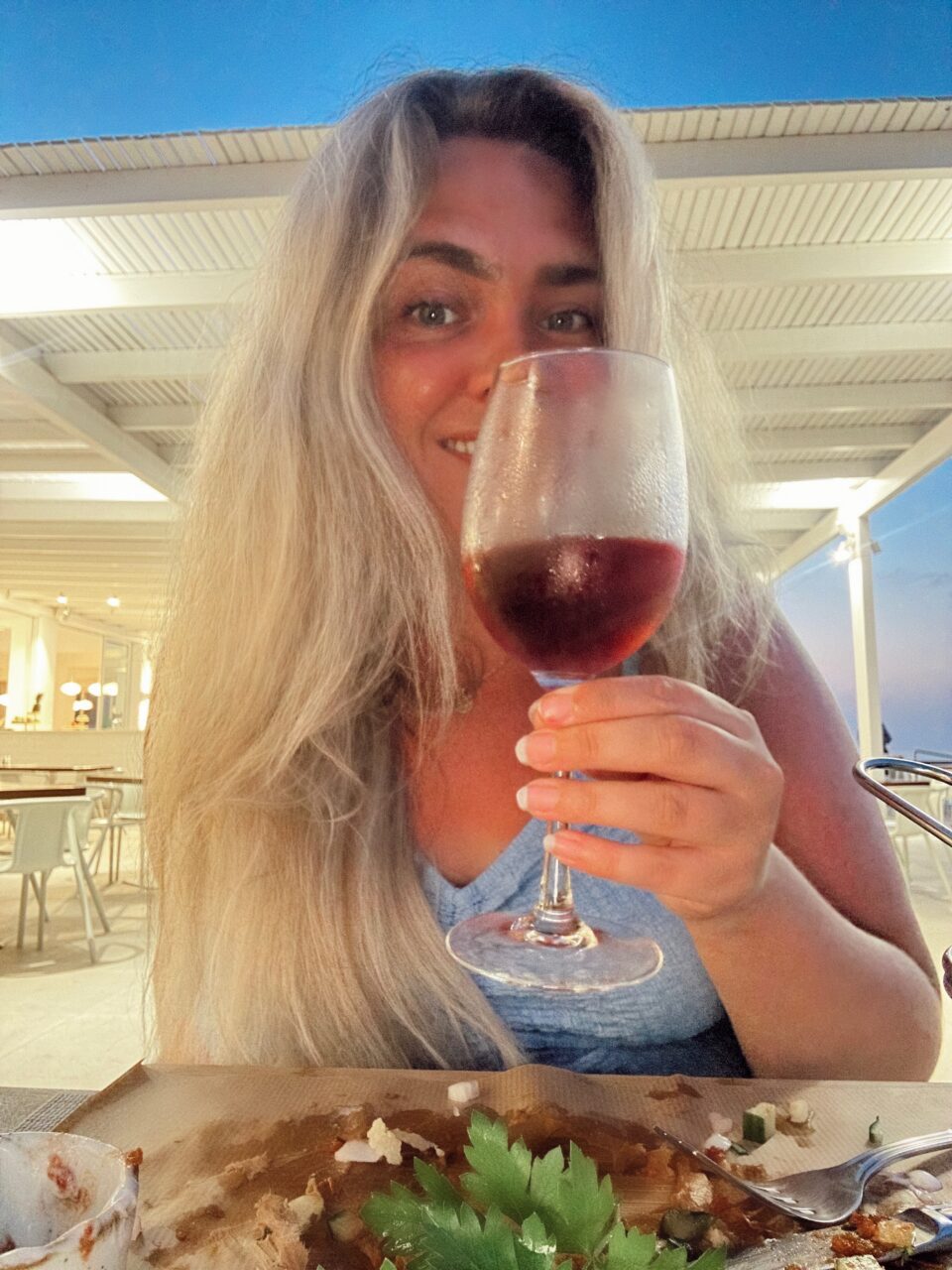 En jente som holder et vinglass mot kamera. Foto