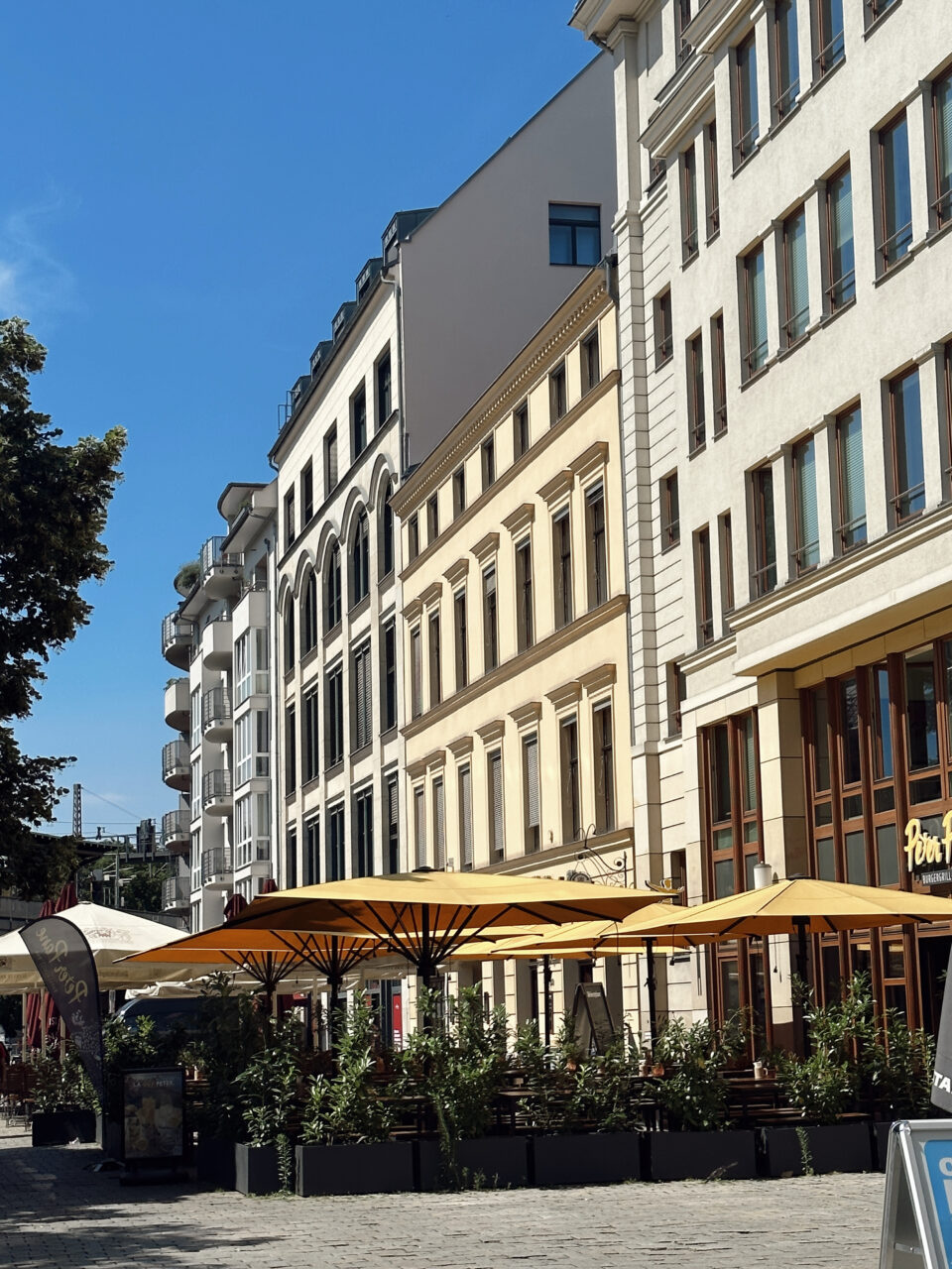 Bygninger som står side om side på et torg med et serveringsområde på forsiden. Foto