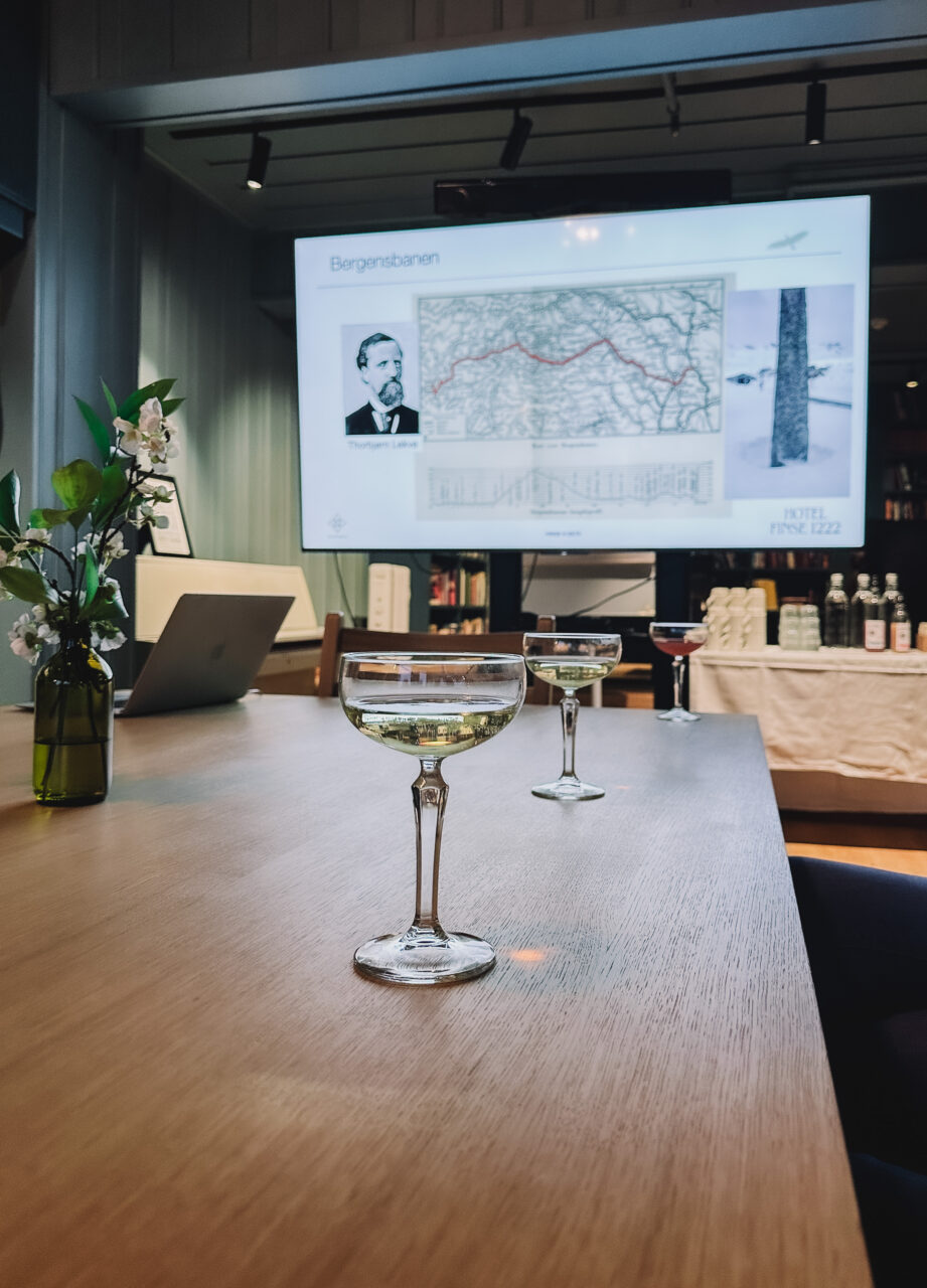 Et glass foran en skjerm som viser historien om Bergensbanen. Foto
