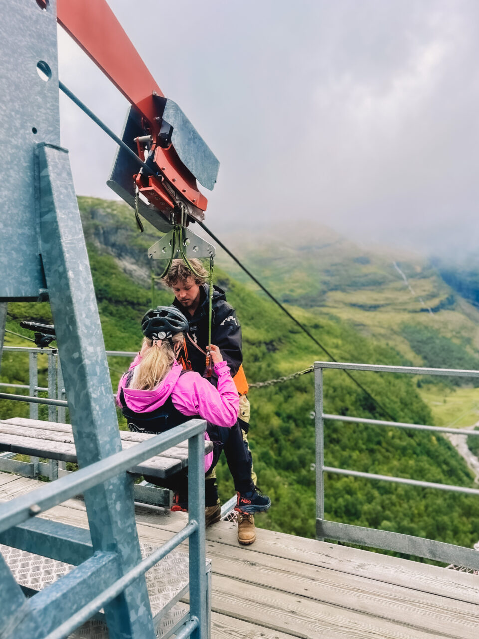 En dame i rosa jakke som skal ta zipline. Foto