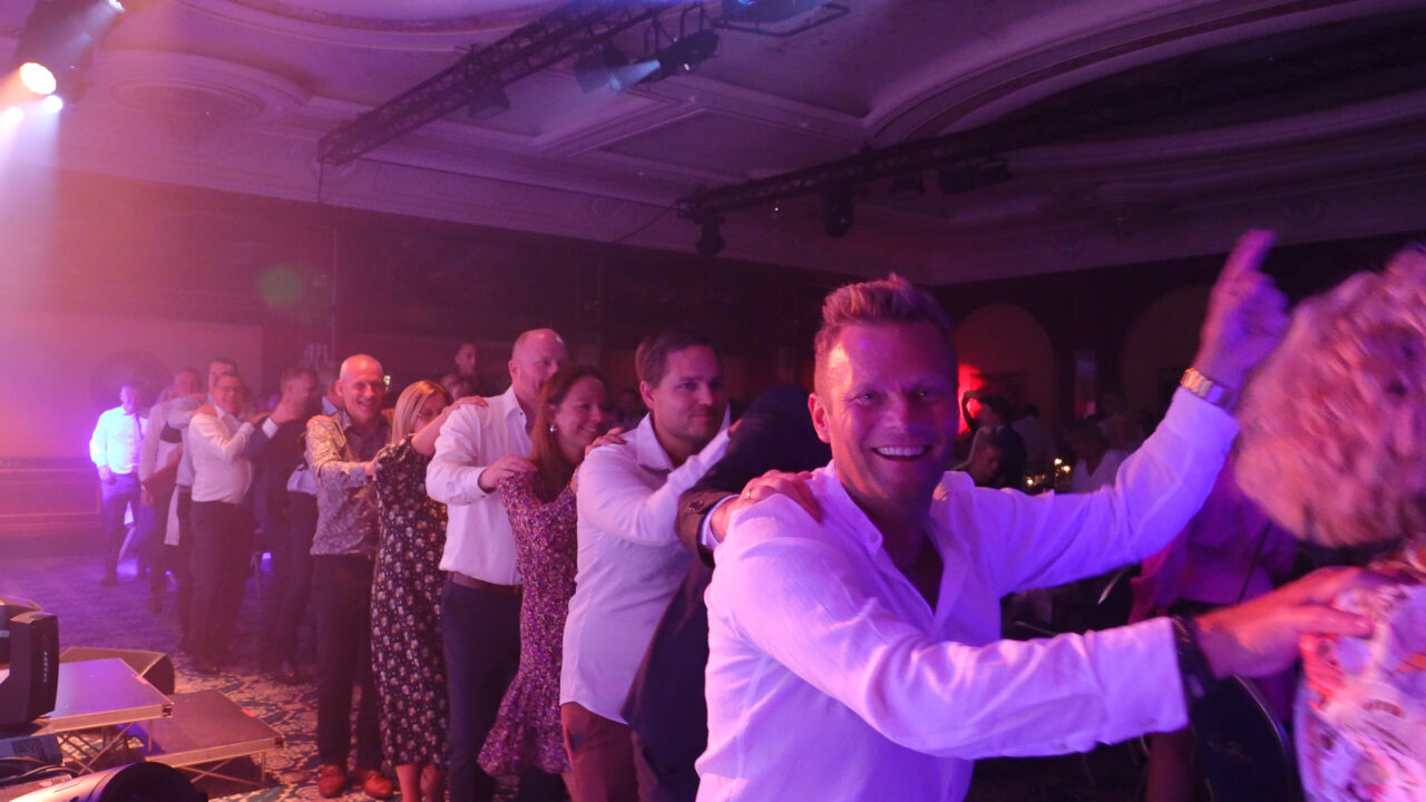 Rekke med mennesker danser og smiler. Foto