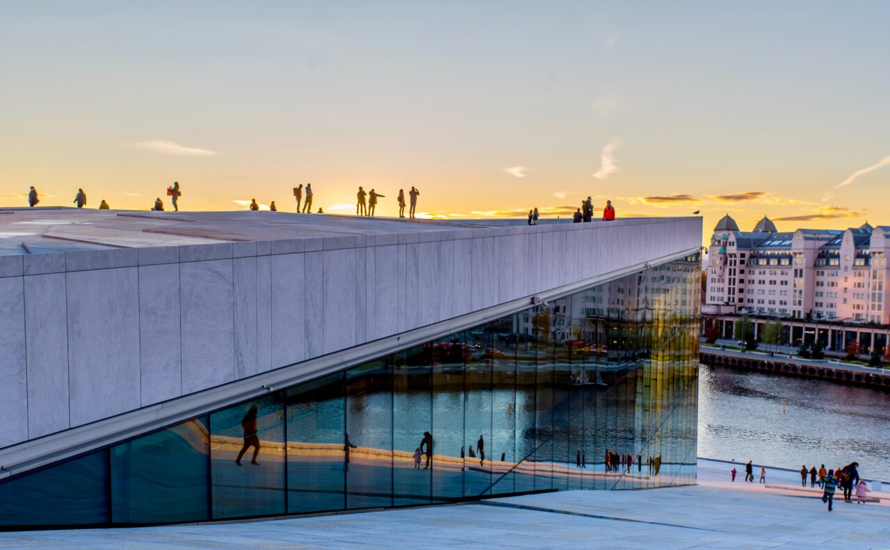Mennesker står på taket på Operaen og ser ut over solnedgangen. Foto