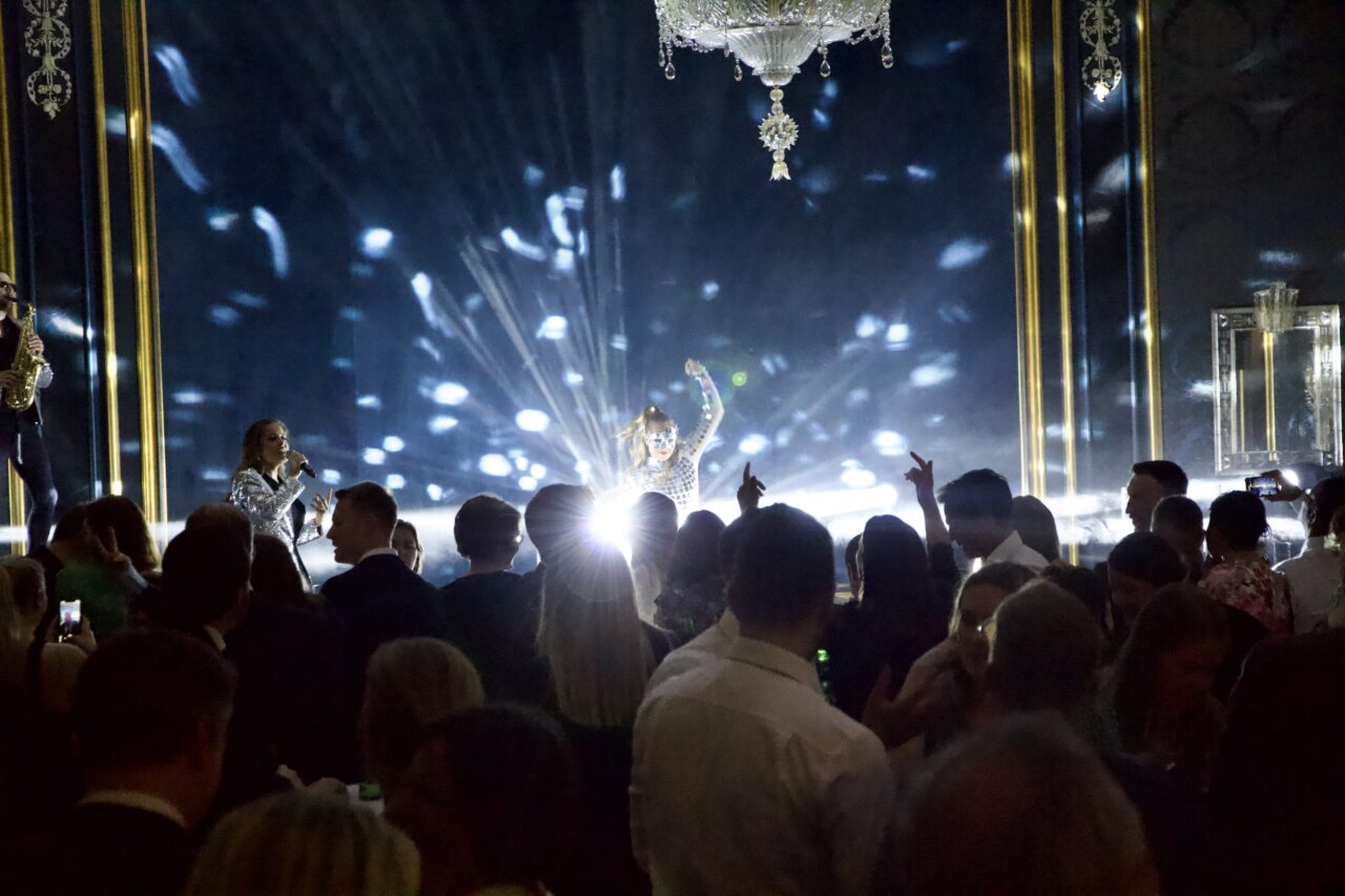 Dansere med discodrakter står på scenen. Foto